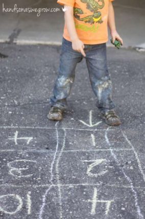 Child stepping through a chalk number maze on a driveway