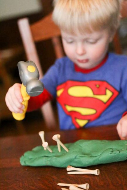 Hammering tees into play dough for toddlers to work on hand and eye coordination