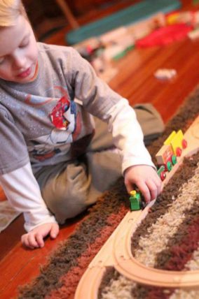 Child playing with wooden toy trains
