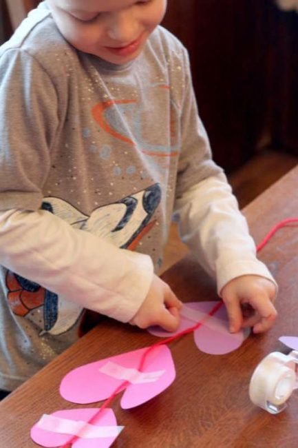 Taping on hearts to string to hang in the window.